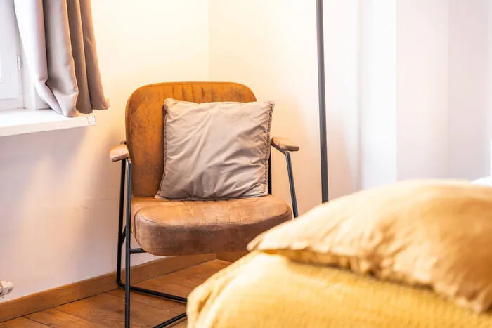 Sillón con cojín ocre junto a la ventana