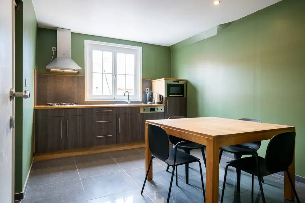 De gedeelde keuken beneden, met kookplaat, waterkoker en een houten tafel
