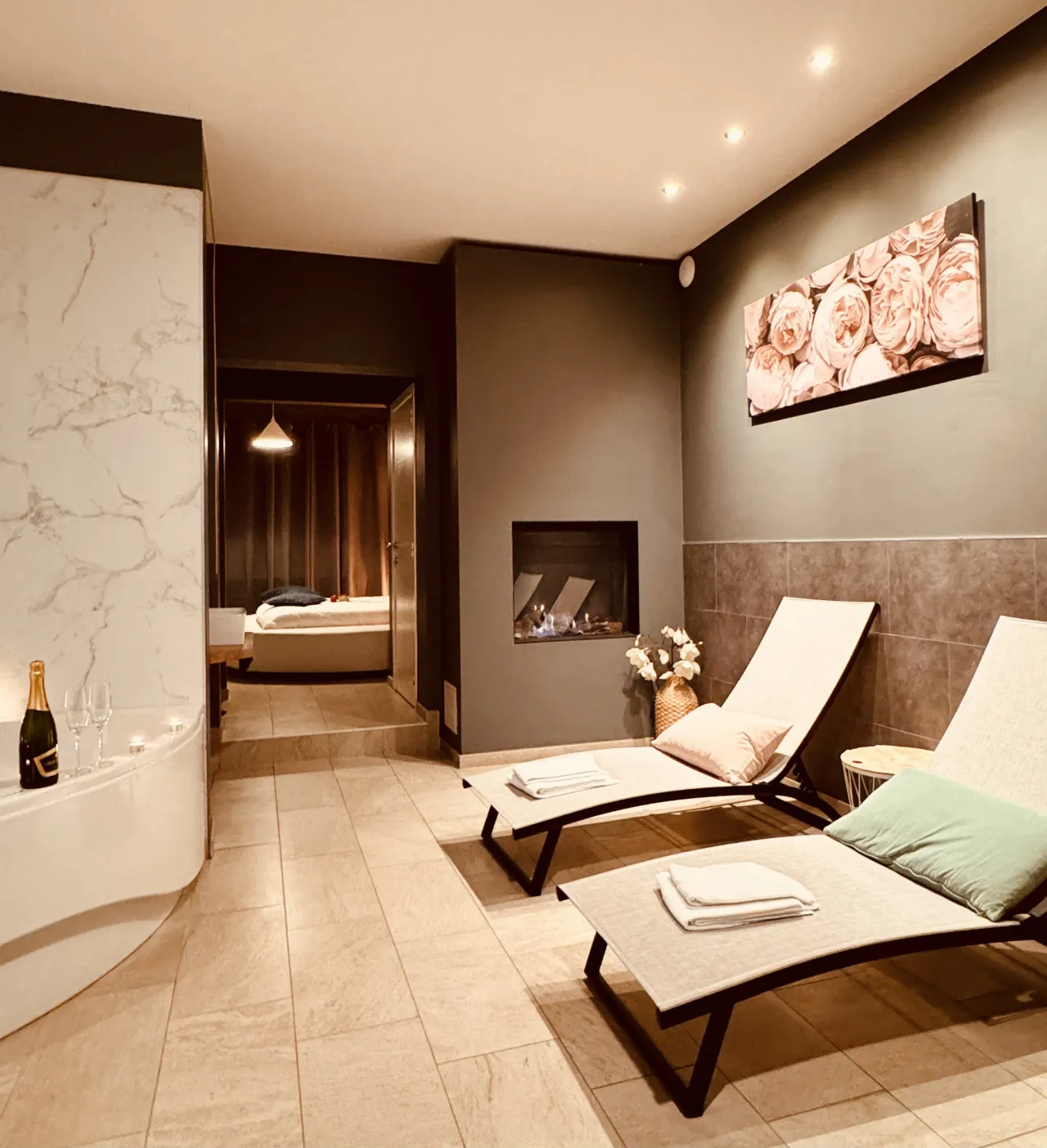 El rincón de relax de la Private Wellness Suite: el borde del jacuzzi, la chimenea eléctrica y dos butacas